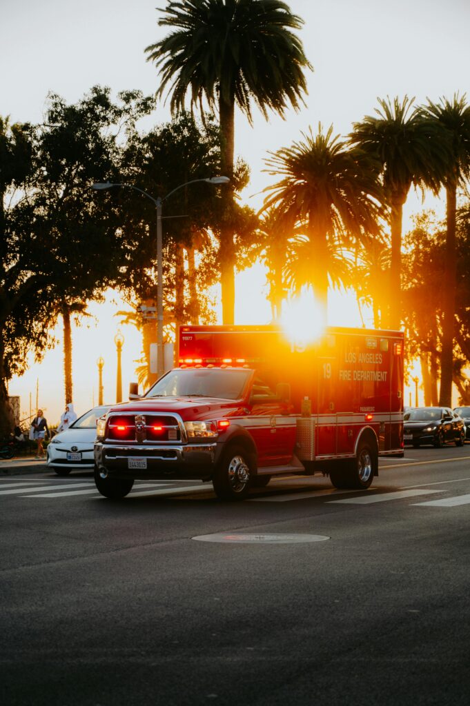 Ambulance driving down a palm lined road at sunset