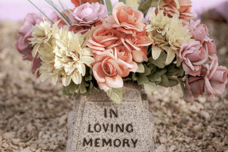 Memorial flowers resting on a headstone engraved In Loving Memory