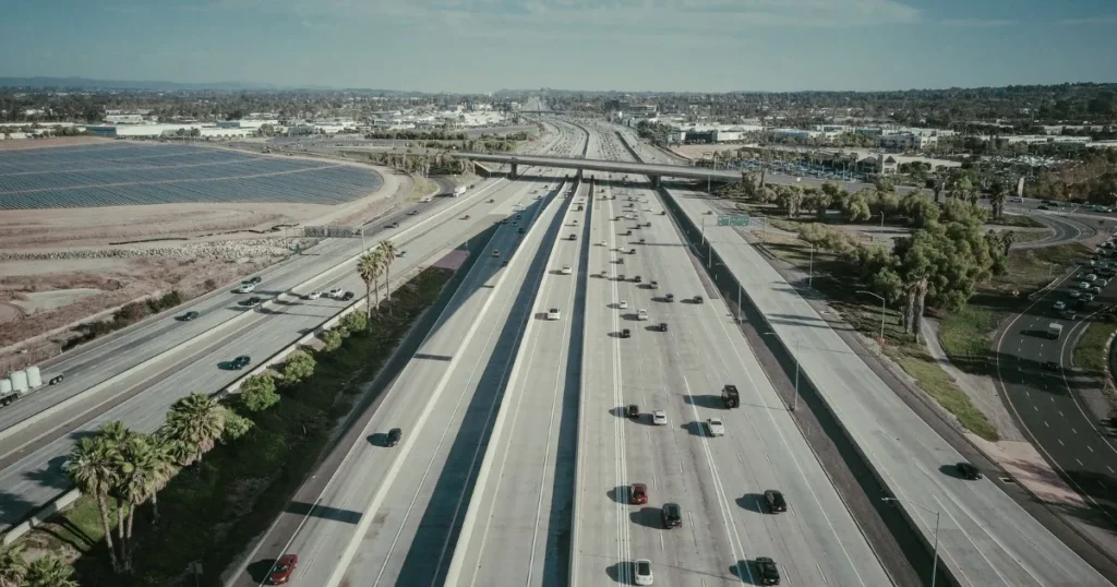 Aerial view of vehicles travelling across several marked lanes of a wide expressway