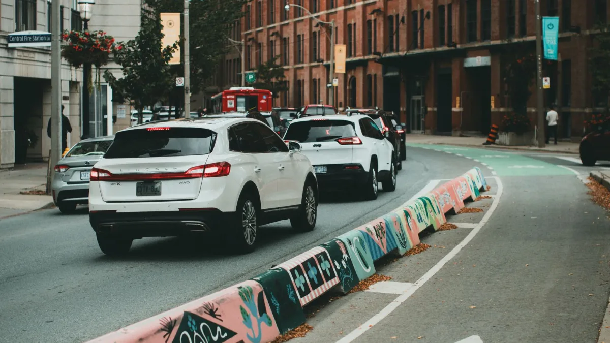 An empty marked bicycle lane running alongside a city street with cars in the adjacent traffic lanes.