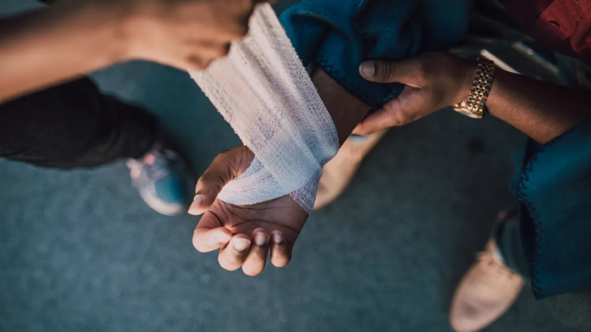 Hands applying a bandage to an injured wrist