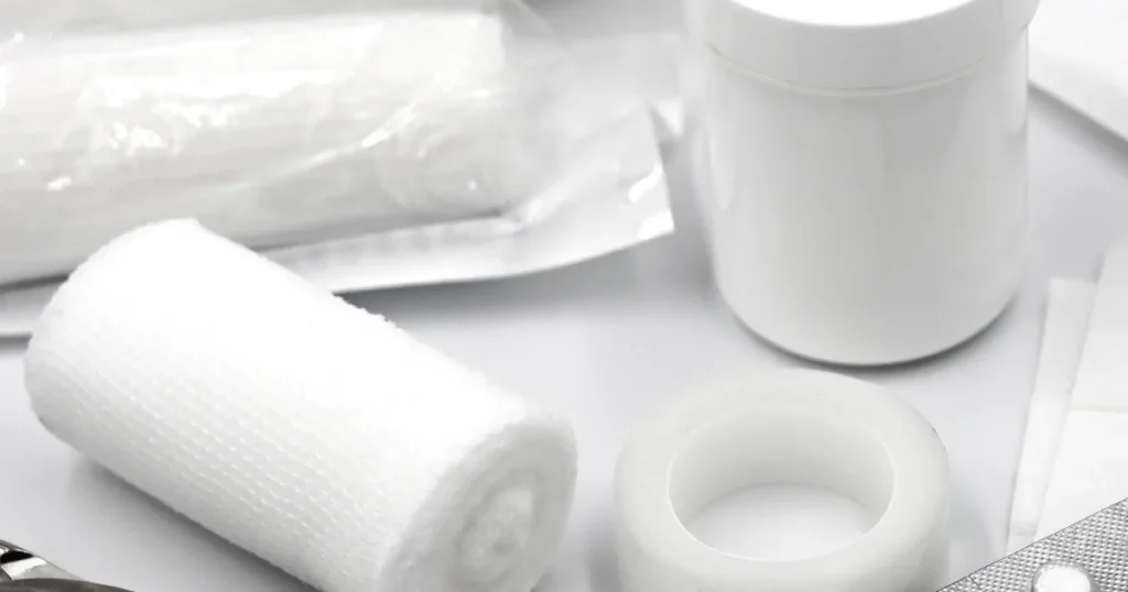 First aid supplies including bandages, gauze and antiseptic laid out on a surface