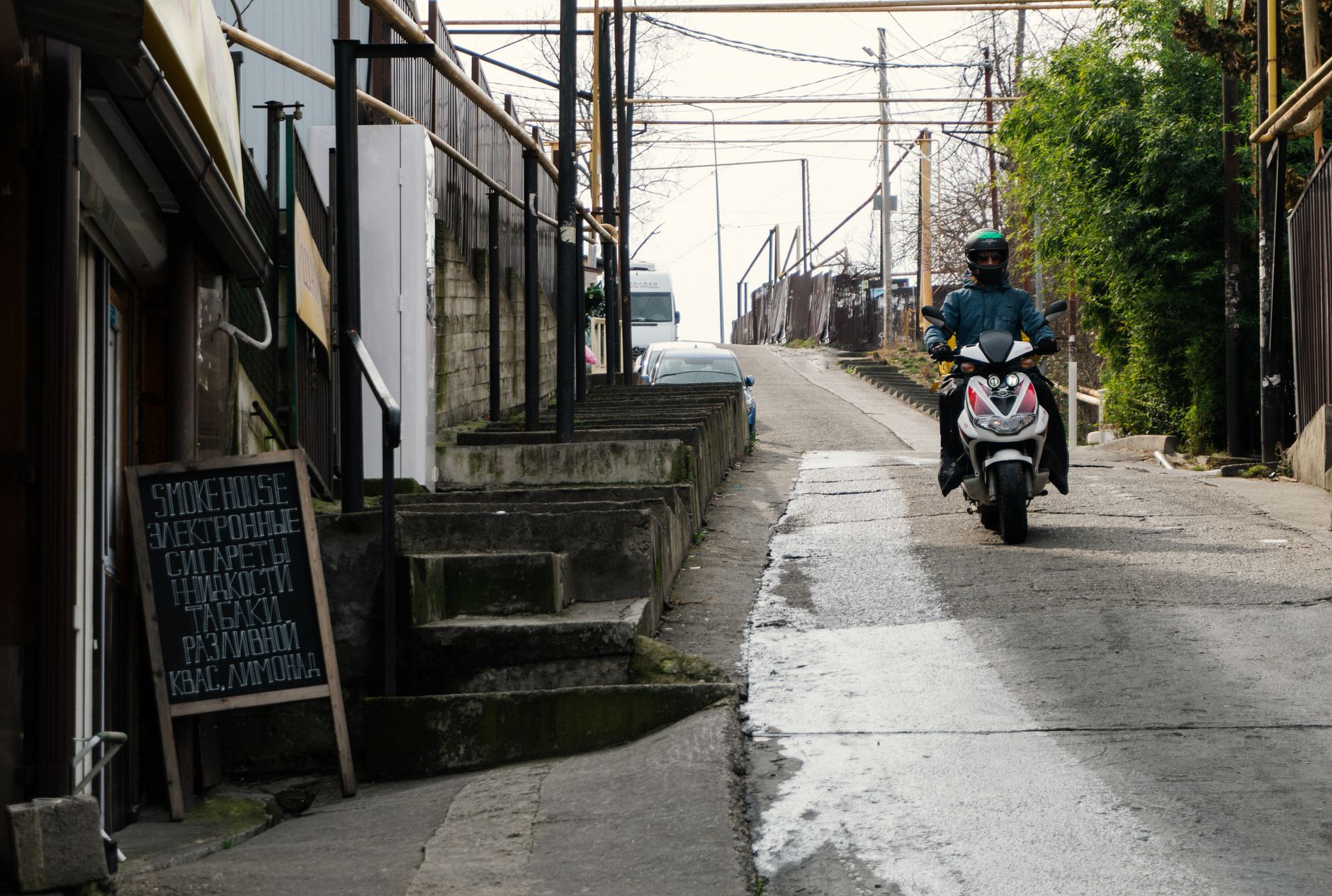 A rider on a small motor scooter moving along a city street in traffic
