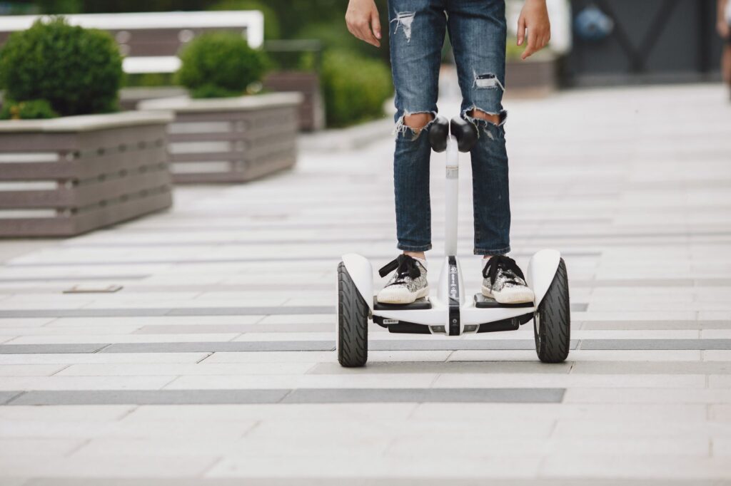 A rider balancing on a two-wheeled hoverboard along a city sidewalk