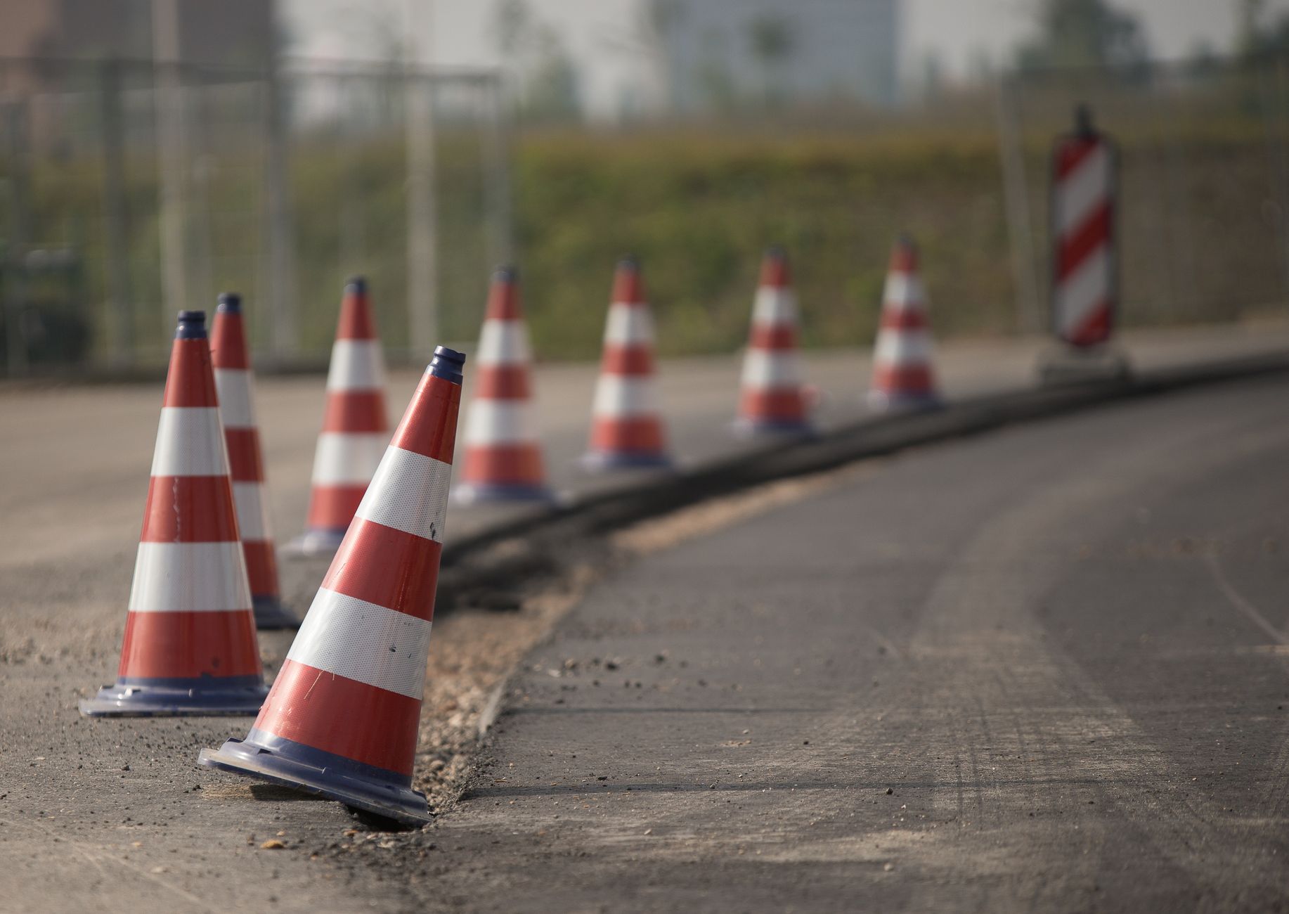 A road maintenance crew working behind orange traffic cones on the shoulder of a highway