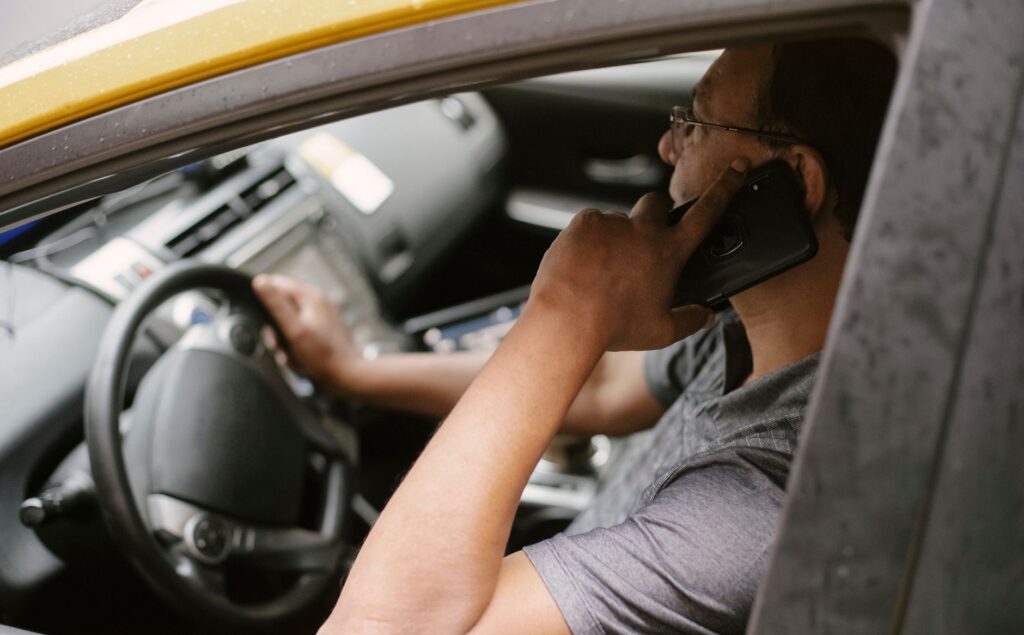 A driver holding a smartphone inside a vehicle
