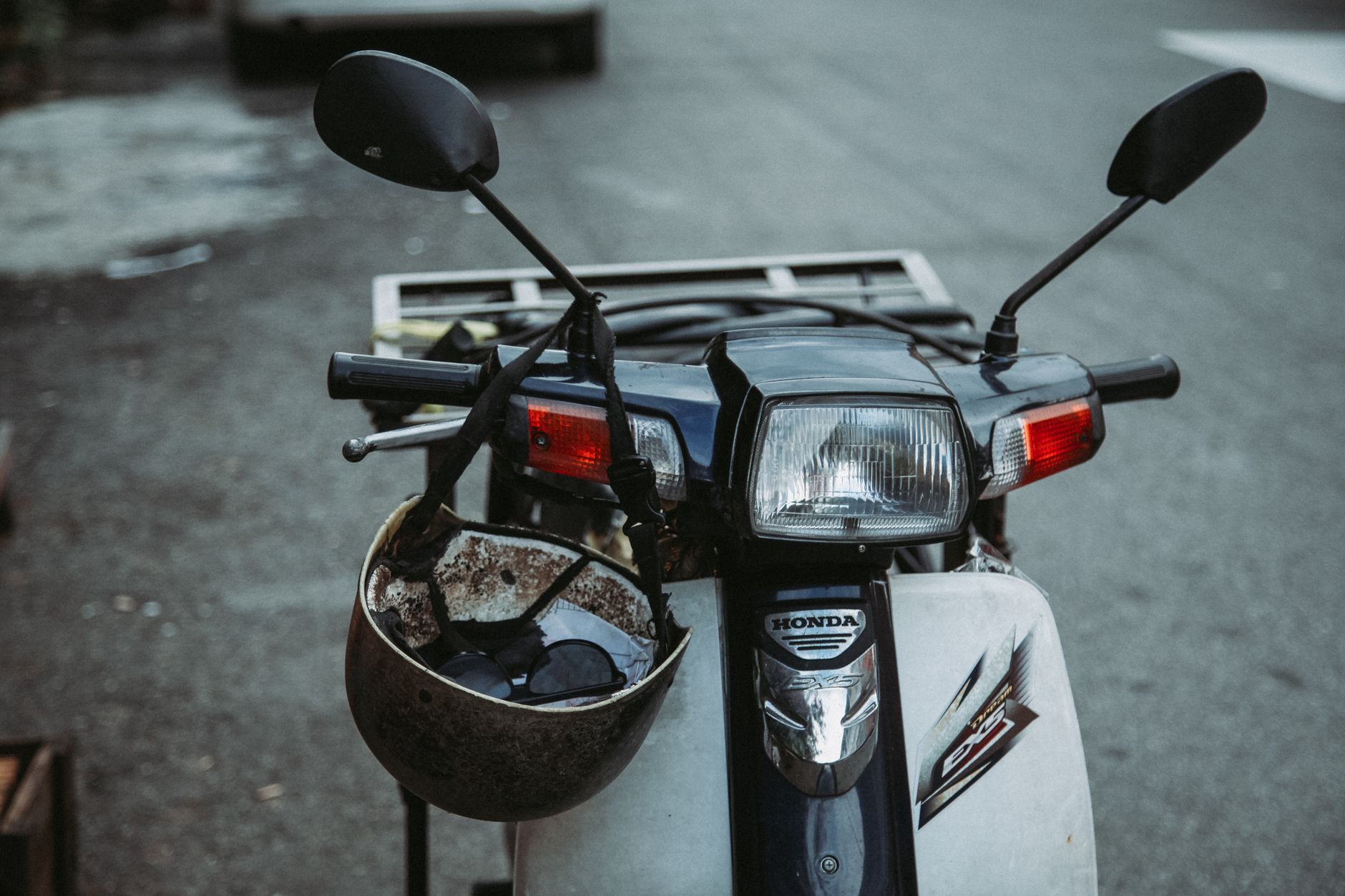 A safety helmet resting on the handlebars of a parked moped