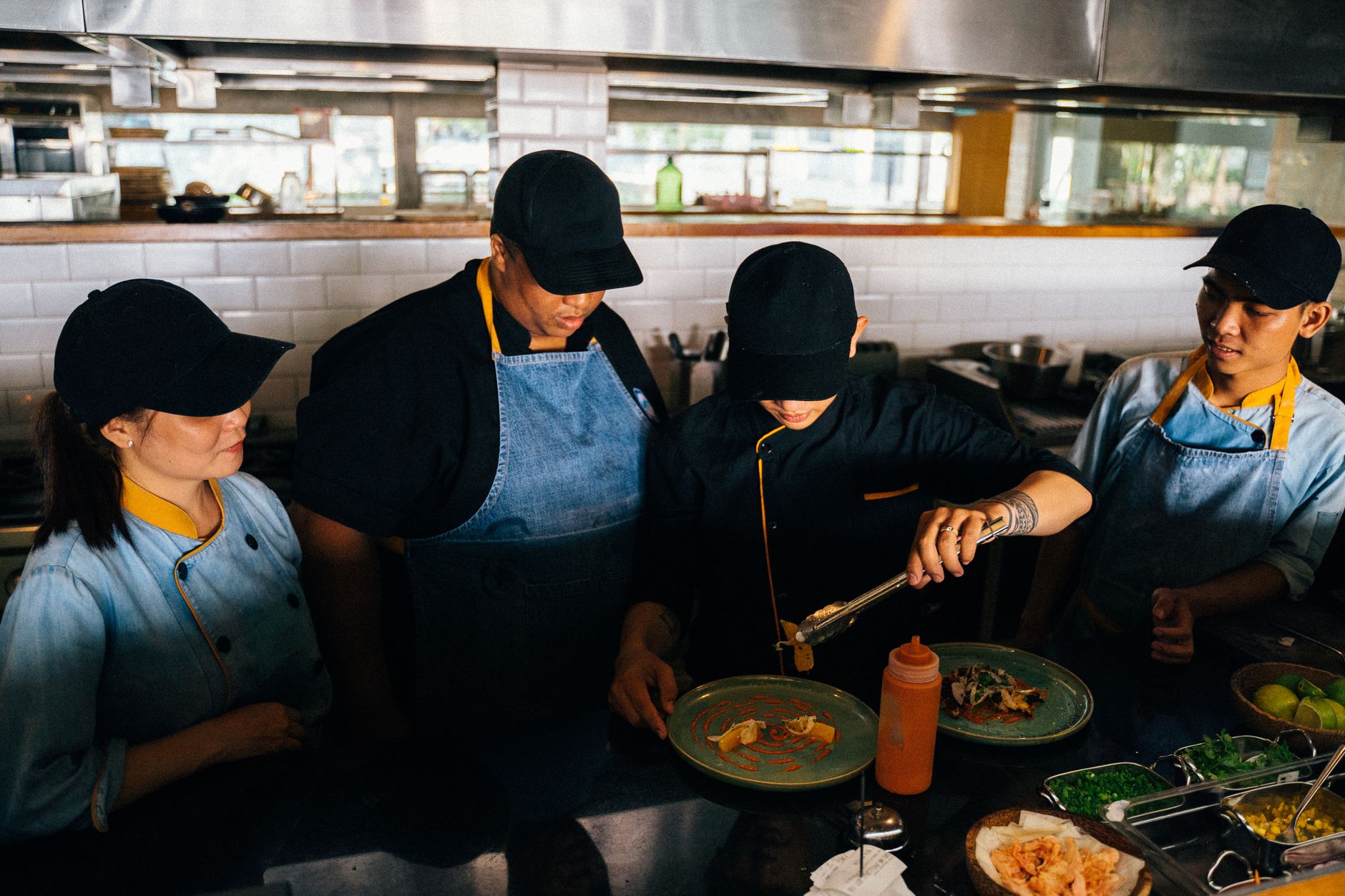 Restaurant kitchen staff preparing plates of food on a service line