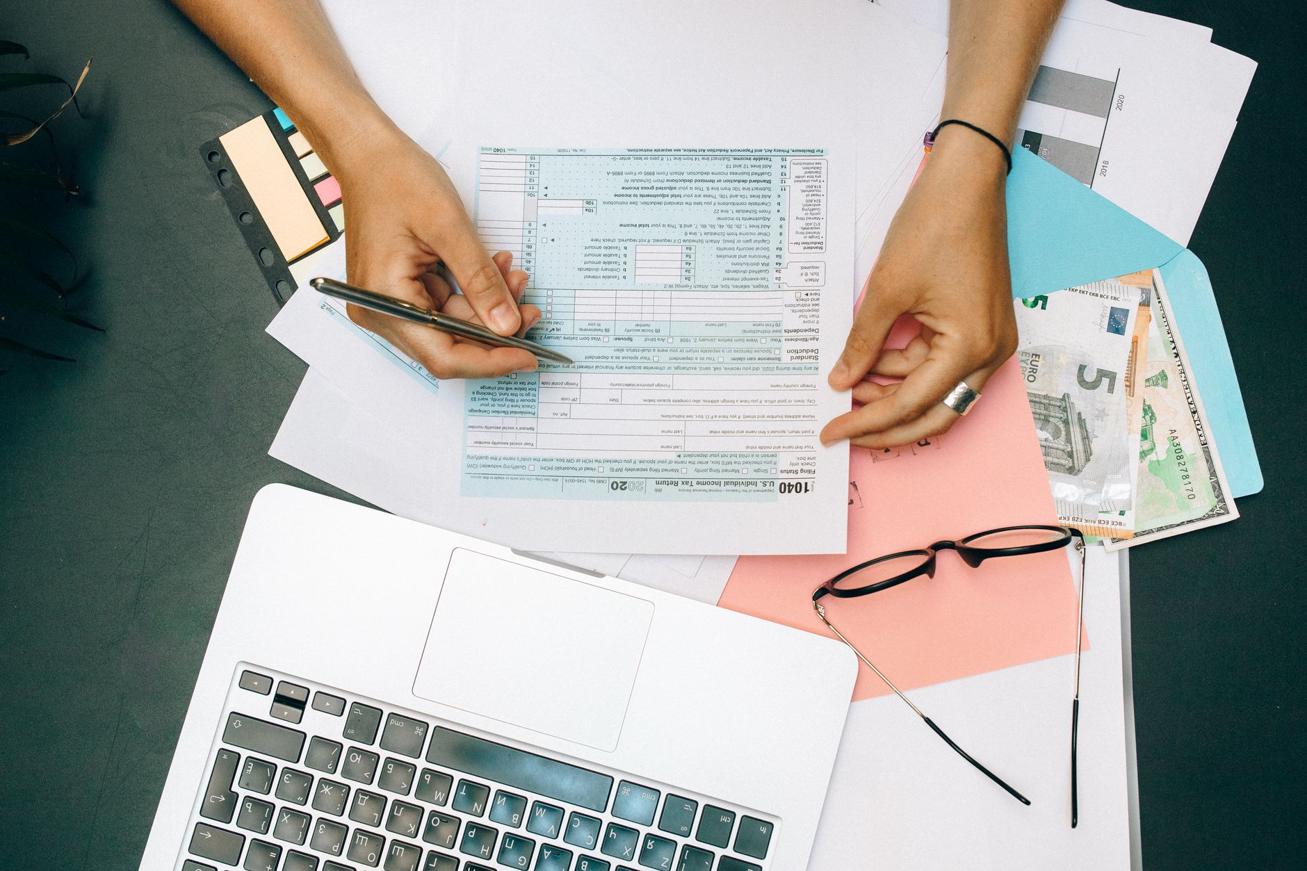 Financial paperwork beside an open laptop