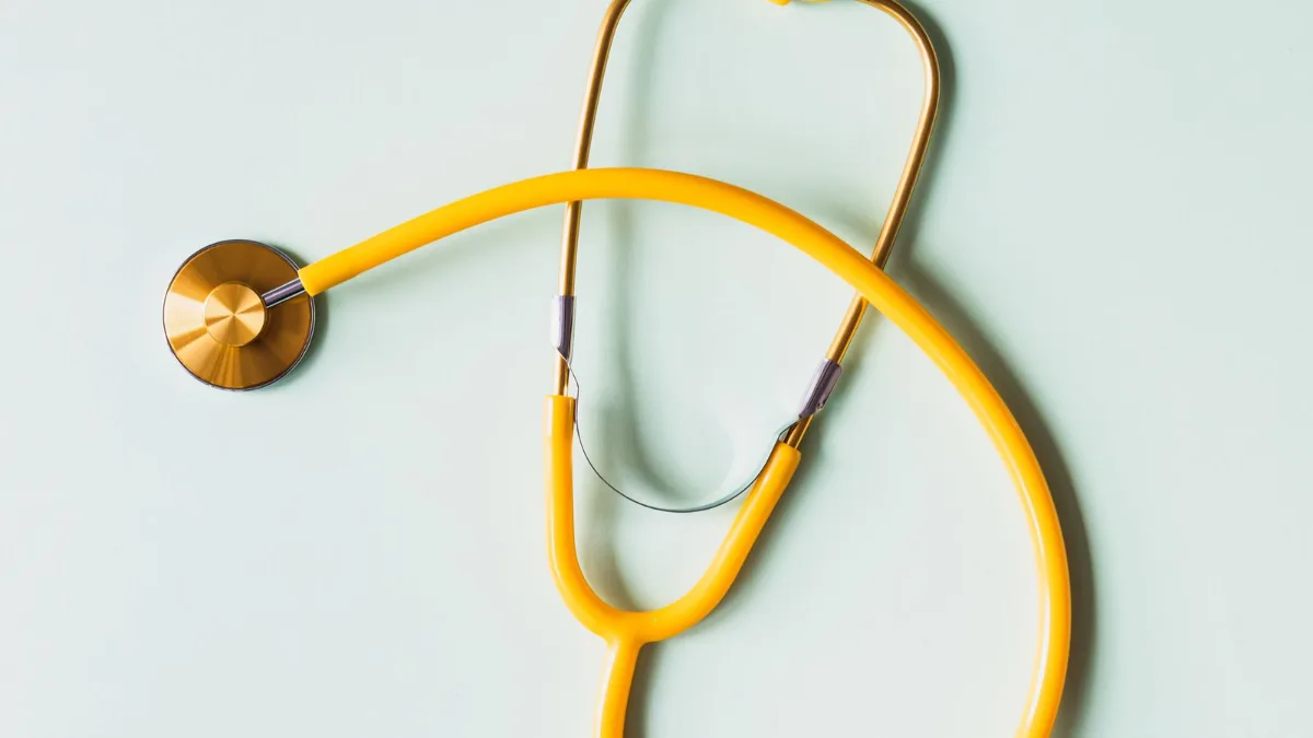 A stethoscope lying alone on a plain white surface.