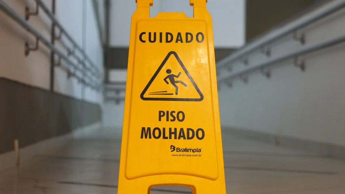 A yellow caution sign warning of a wet floor in a tiled corridor