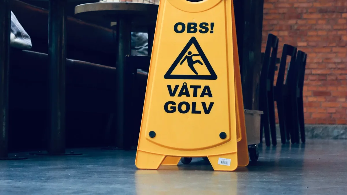 A yellow caution wet floor sign standing on the tiled floor of a cafe.
