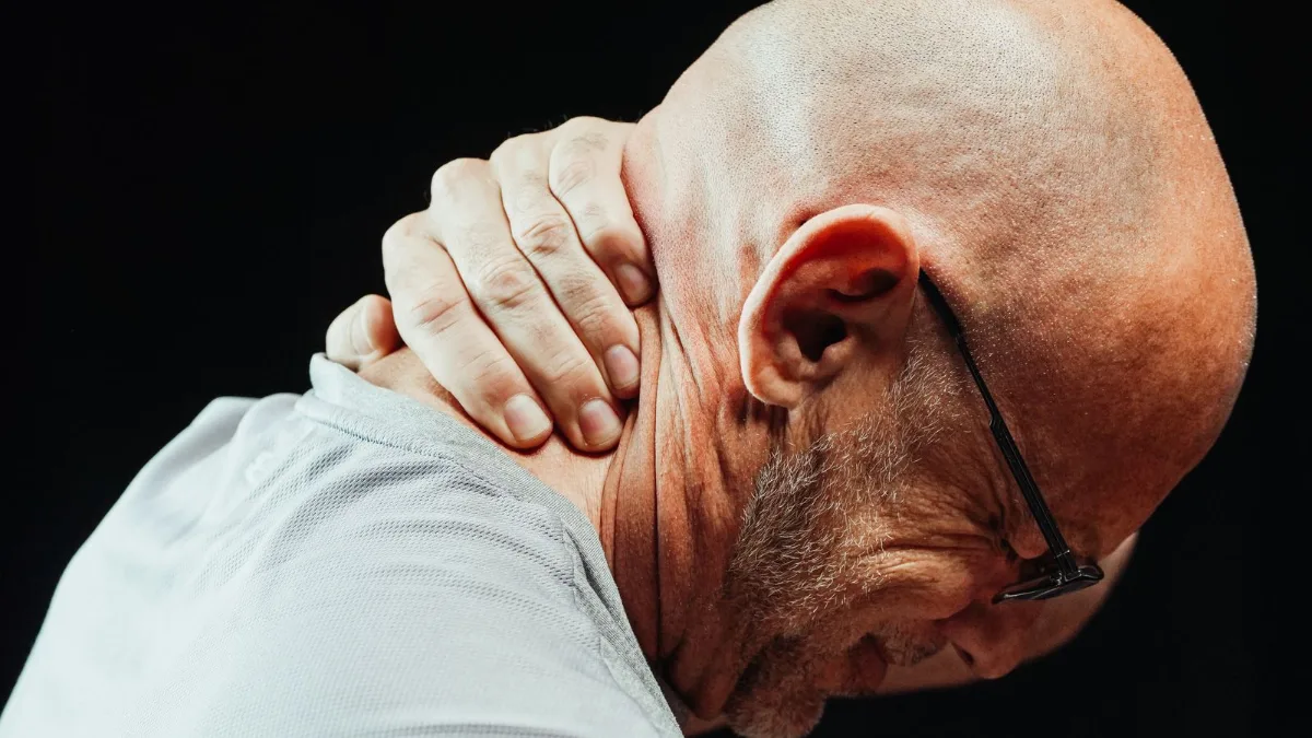 A man holding the side of his neck in discomfort
