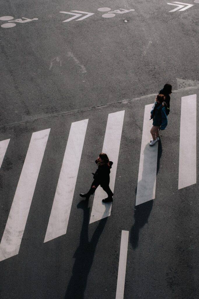 Pedestrians crossing a city street in a marked crosswalk, seen from above