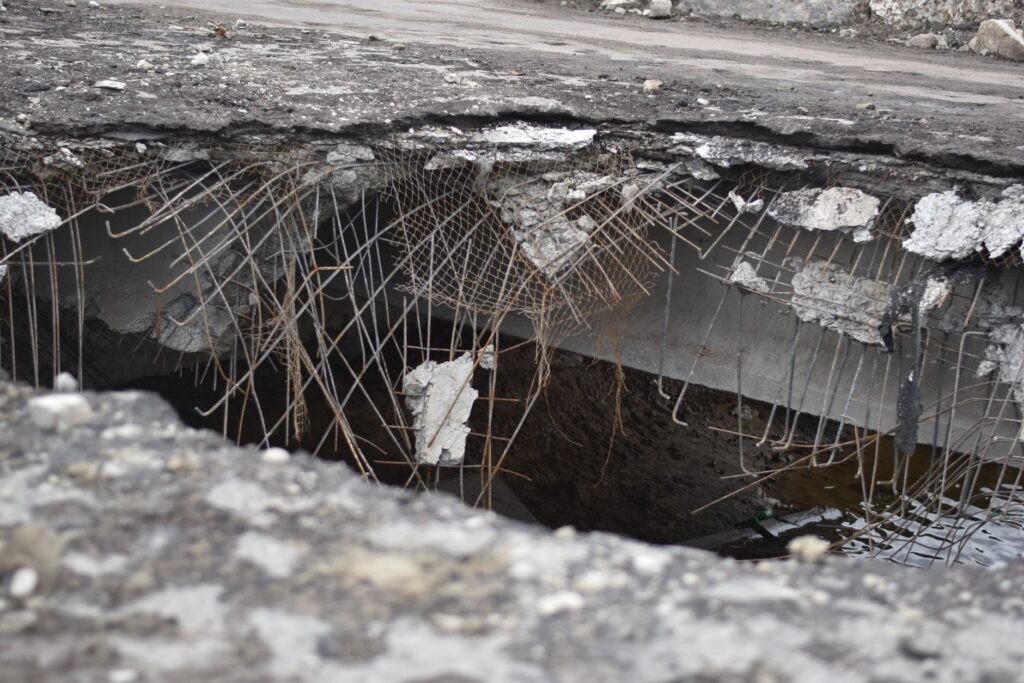 Broken pavement and a pothole in a city roadway