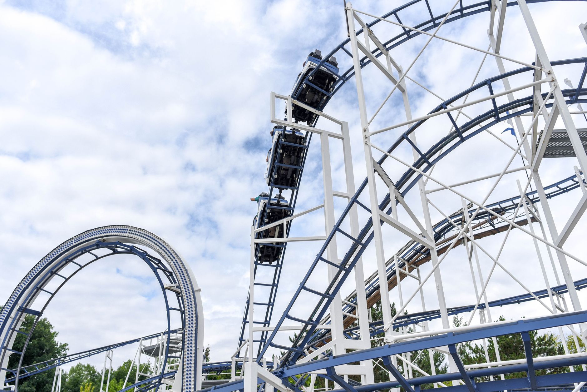 White roller coaster track curving above an amusement park