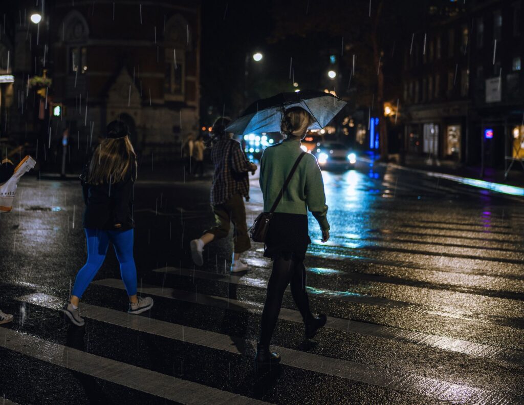 A pedestrian crossing a street away from an intersection at dusk