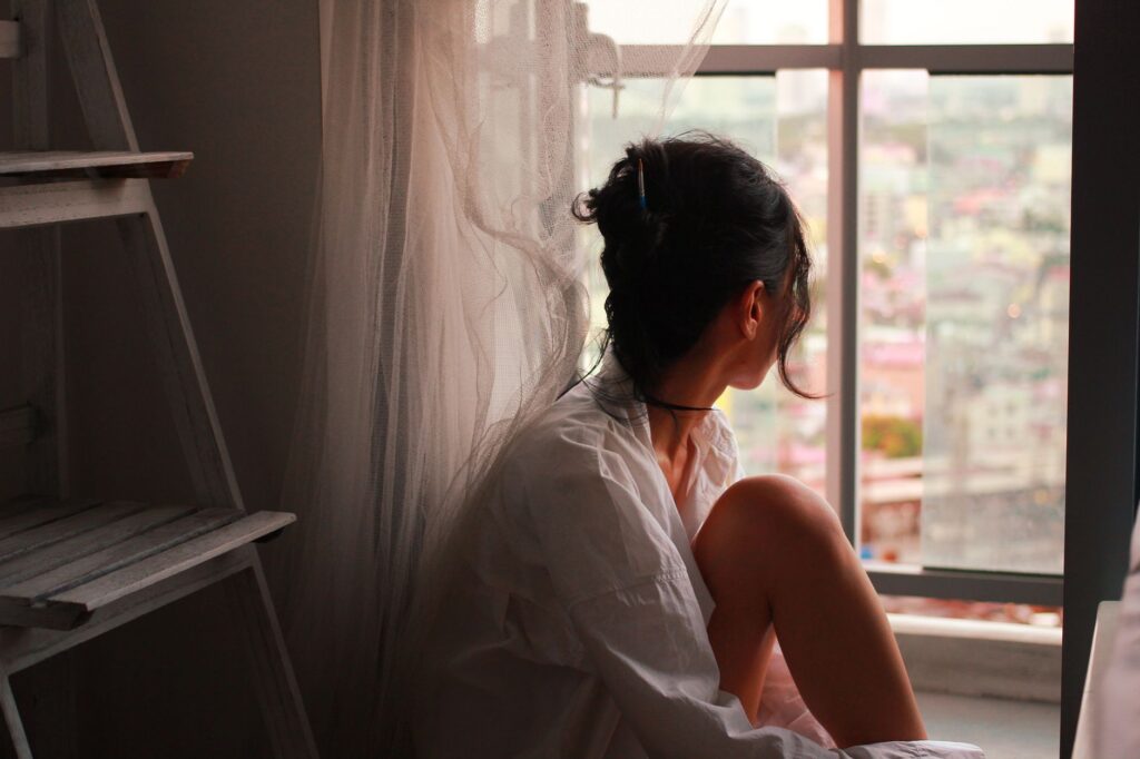 A person sitting quietly by a window during a long recovery from injury