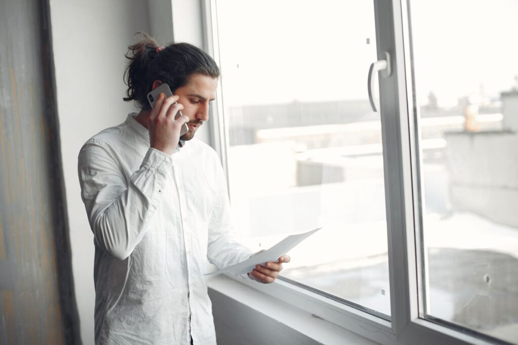 A man on a phone call holding a document