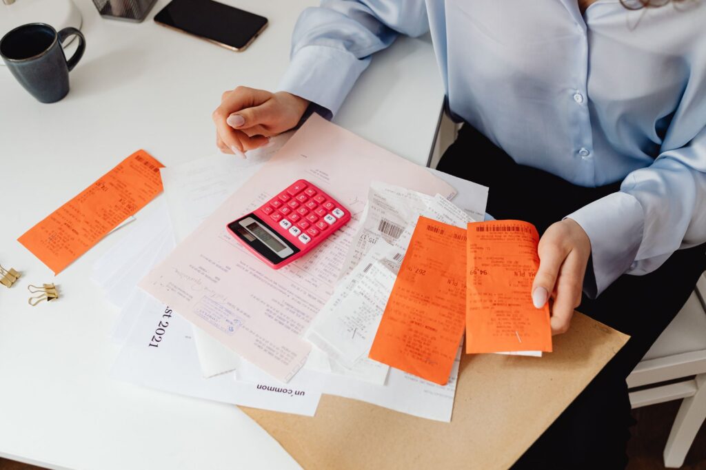 A woman reviewing receipts and adding up expenses at a desk